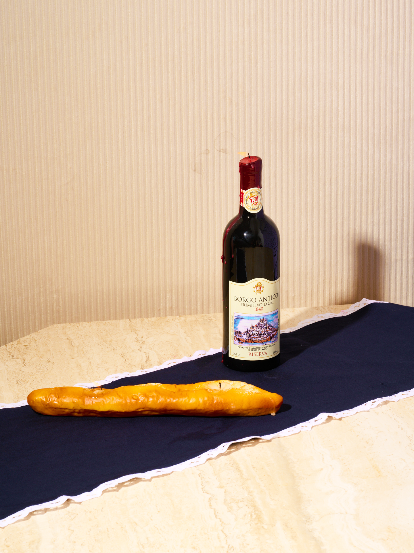 Wine Bottle Candle and Baguette Candle sit atop a lace trim table runner.