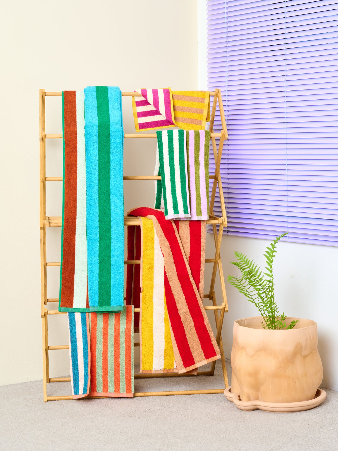 Wooden towel rack with the Earth Stripe Bath and Hand Towel collection by Dusen Dusen sits next to a Jumbo Nude Bottom Pot.