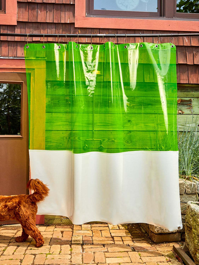 Coming Soon x Quiet Town Zinc shower curtain with a vibrant transparent green top and opaque white bottom pictured hanging outside.