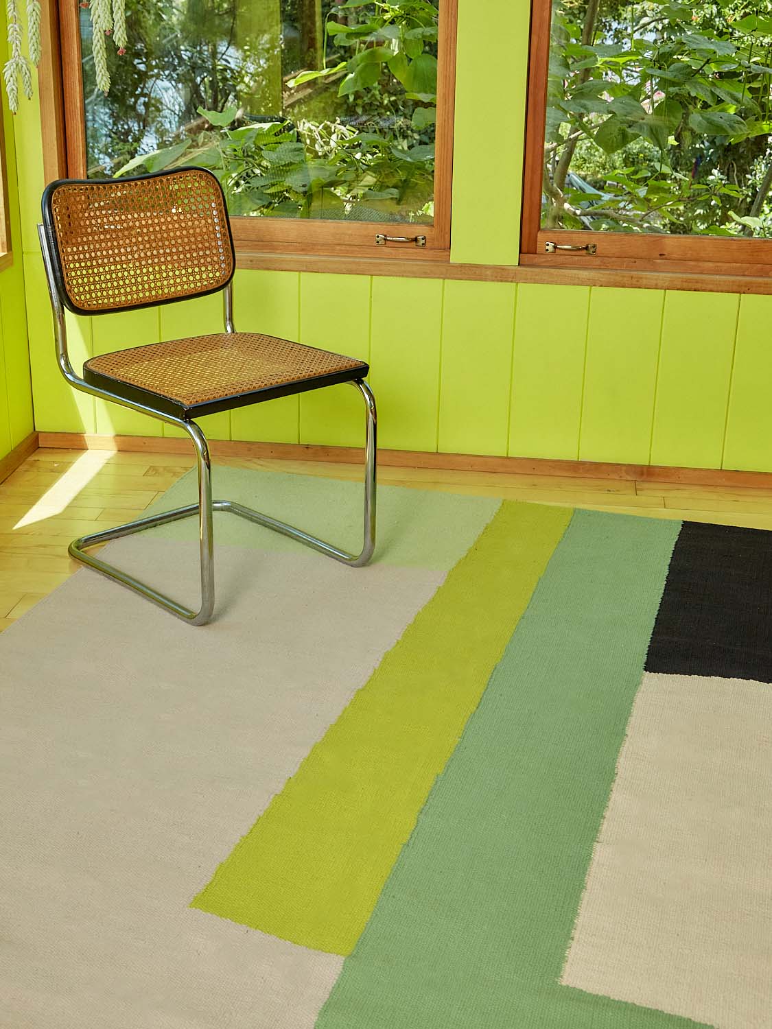 A black Cesca Chair sits atop the corner of the Earthworm Rug.