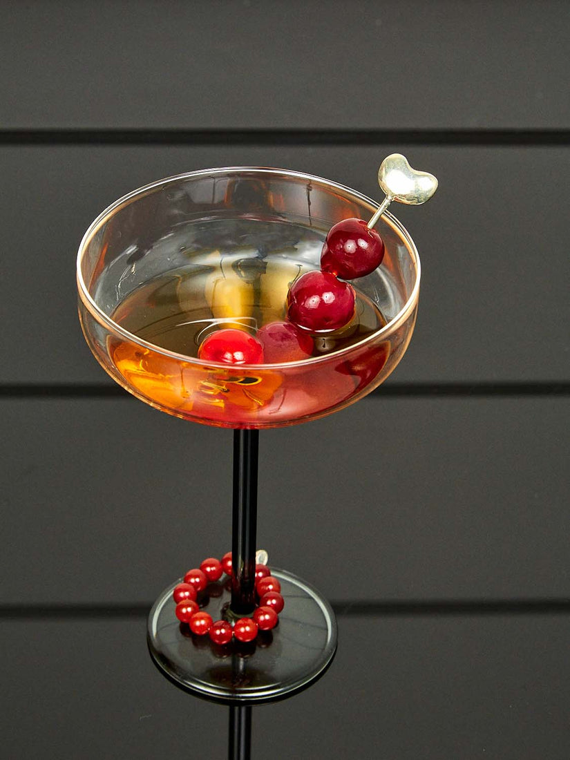 A Bean Toothpick full of cherries in a Manhattan Glass wearing a Bracelet for Stemware.
