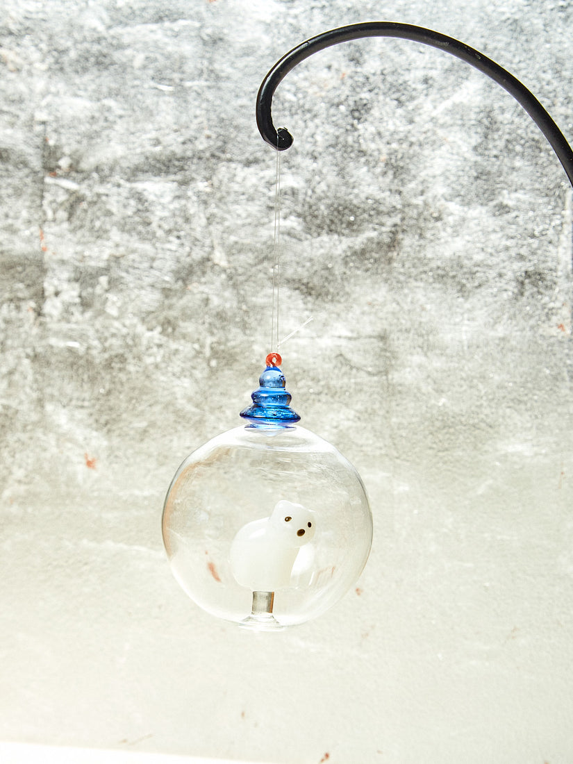 Glass ornament with white bear inside and blue tree on top.