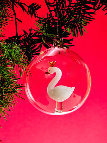 Clear Christmas ornament with a white swan design on a red background