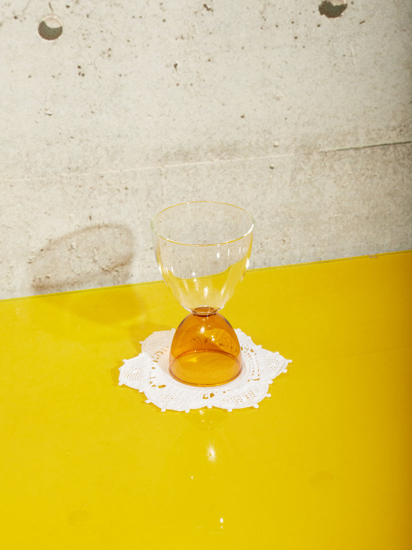 A clear top amber bottom cocktail glass.