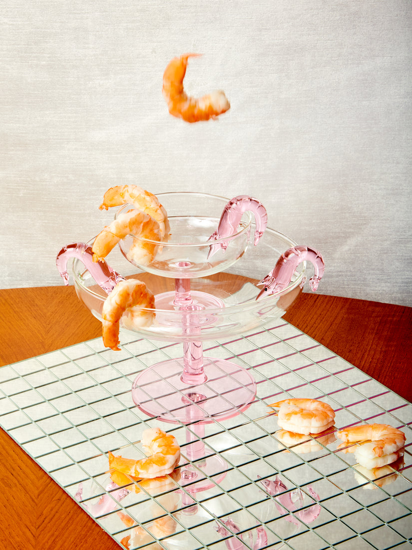 Shrimp falling and landing in and around a stack of Shrimp Cocktail Coupe and Platter by Maison Balzac.