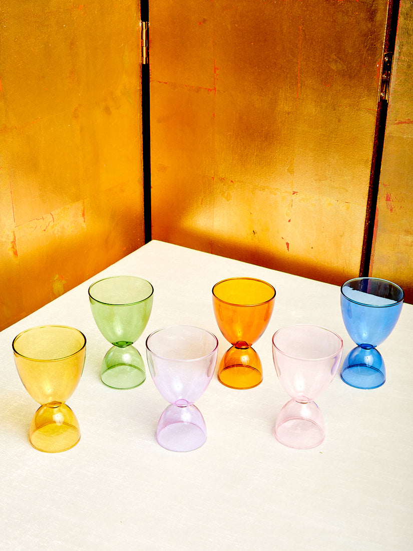 Six monotone cocktail glasses by Mamo in different colors. From left to right: honey, green, lavender, amber, pink, and blue.