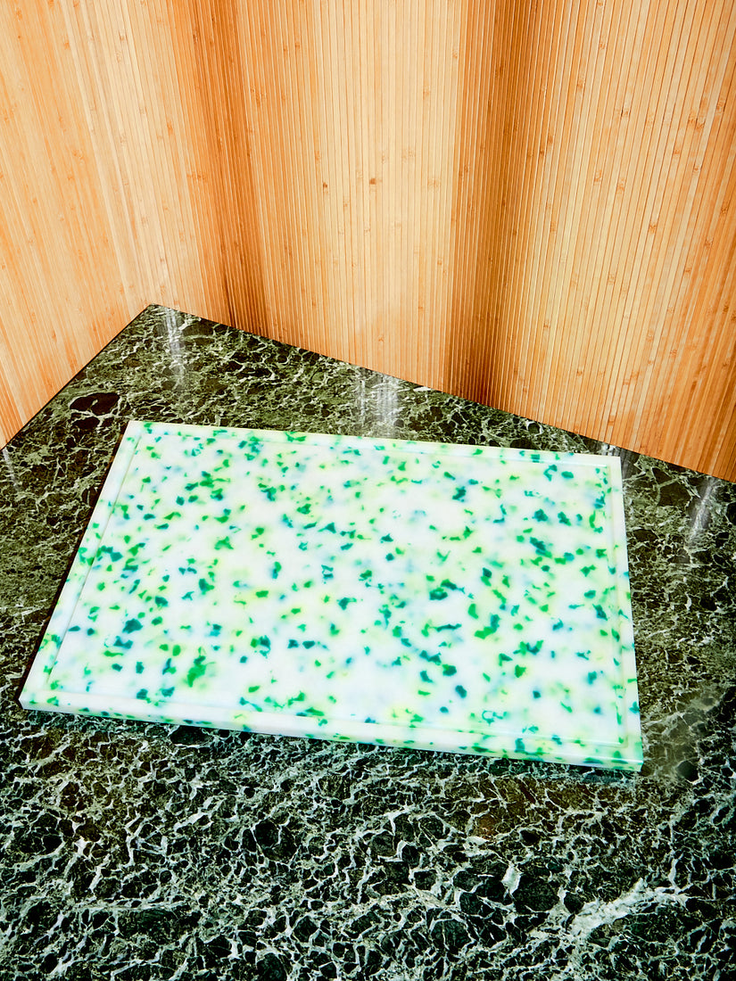 A jumbo green chopping block on a marble table top.
