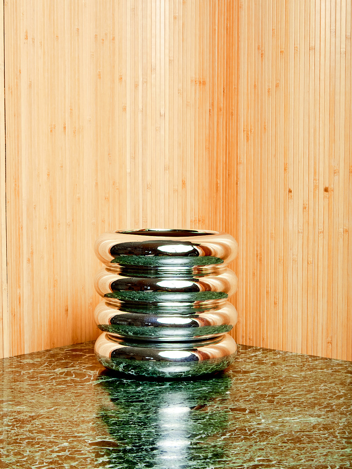 Chrome Stacking Planter by Chen and Kai for Areaware on a green marble table against a slatted wood backdrop.