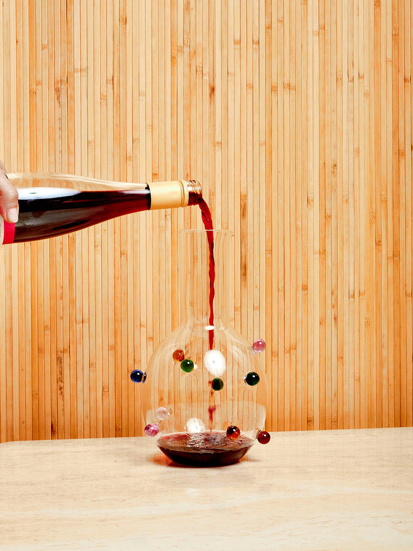 A bottle of red wine decanting into a Dot Carafe by Maison Balzac.