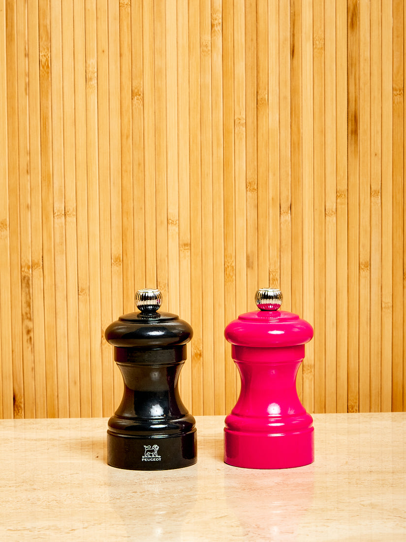 One black and one pink Salt and Pepper Mill by Peugeot.
