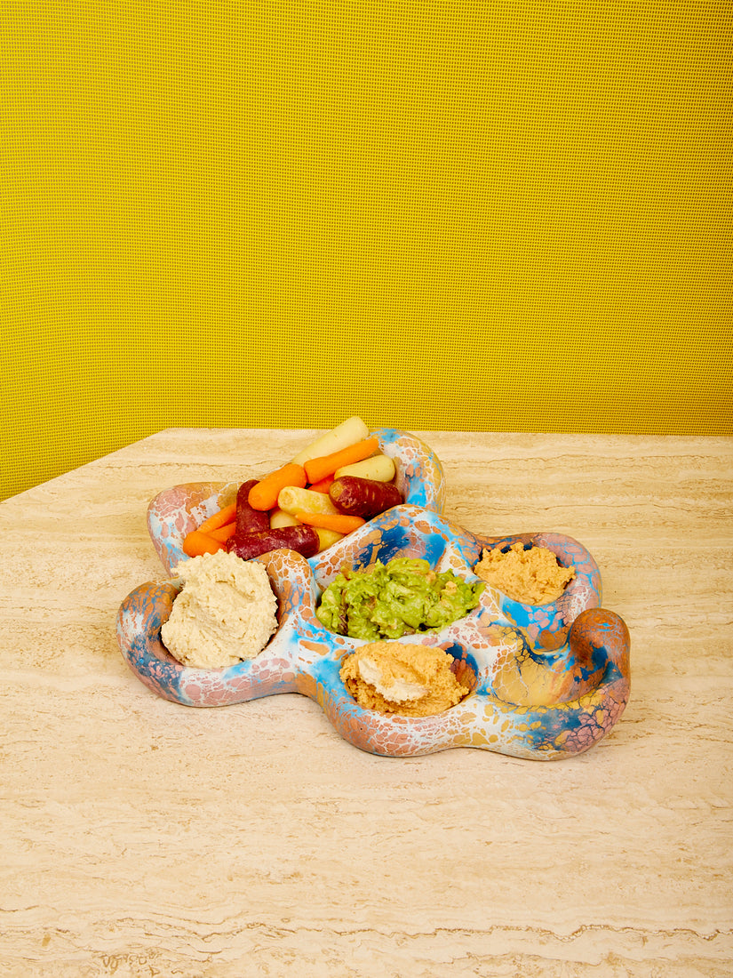 The Aphrodite Trinket Tray by Concrete Cat in blue multicolor full of humus, guac, and carrot sticks.