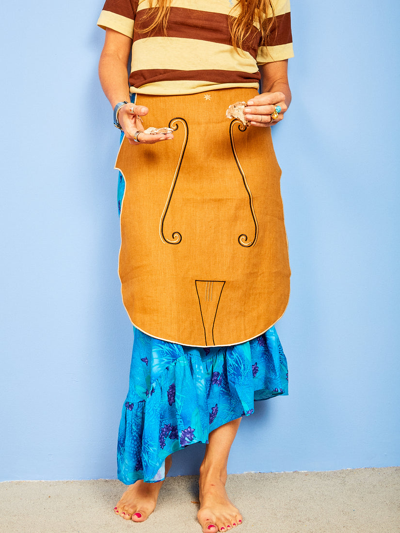Someone wears the Cello Apron by Maison Balzac while holding cookies.