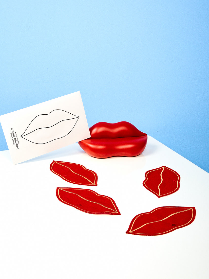 Four Red Bisous lip napkins with a foam lip sculpture and the napkins envelope packaging.