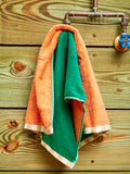 A teal and coral hand towel hanging on a faucet.