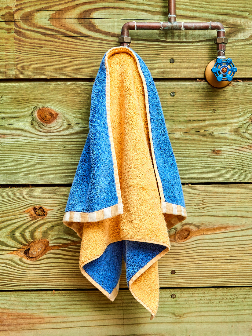 A peach and royal blue hand towel hanging on a faucet.