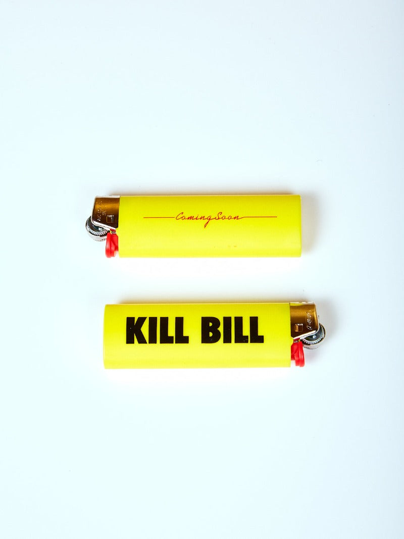 Two yellow lighters laying on opposite sides showing the two prints "KILL BILL" and a red Coming Soon logo.