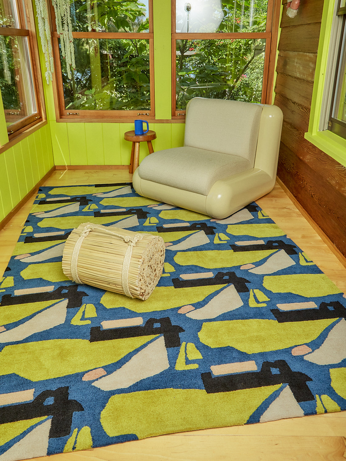 A cream Uma T4 Chair, wooden stool, and rattan stool sit atop a Holy Smoke Rug by Cold Picnic.