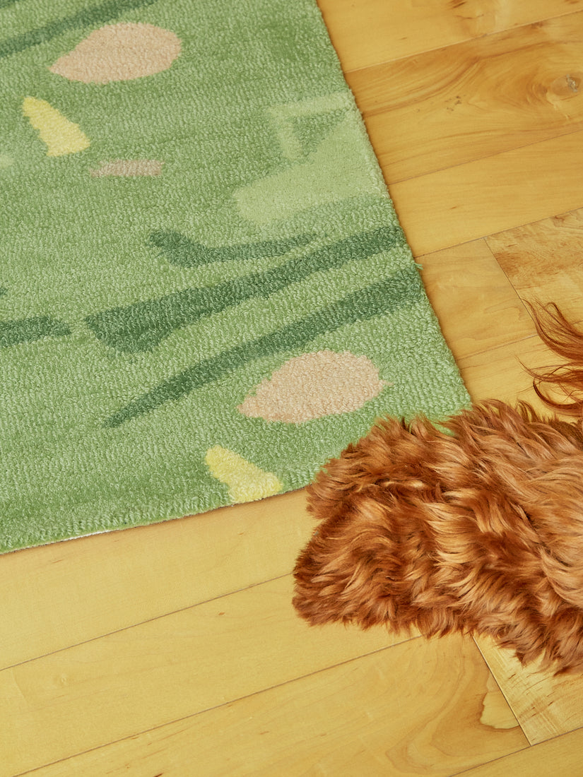 A fluffy pair of paws meet the corner of a Sweetie Rug on a hardwood floor.