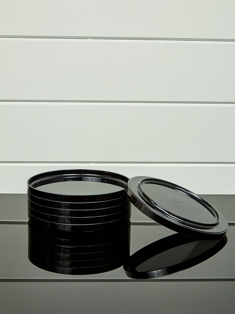 A stack of black dinner plates by Heller with one laying and leaning upside down.