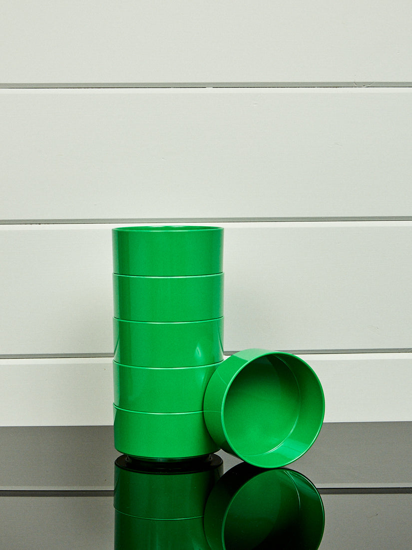 A stack of green bowls by Heller with a single bowl laying on its side.