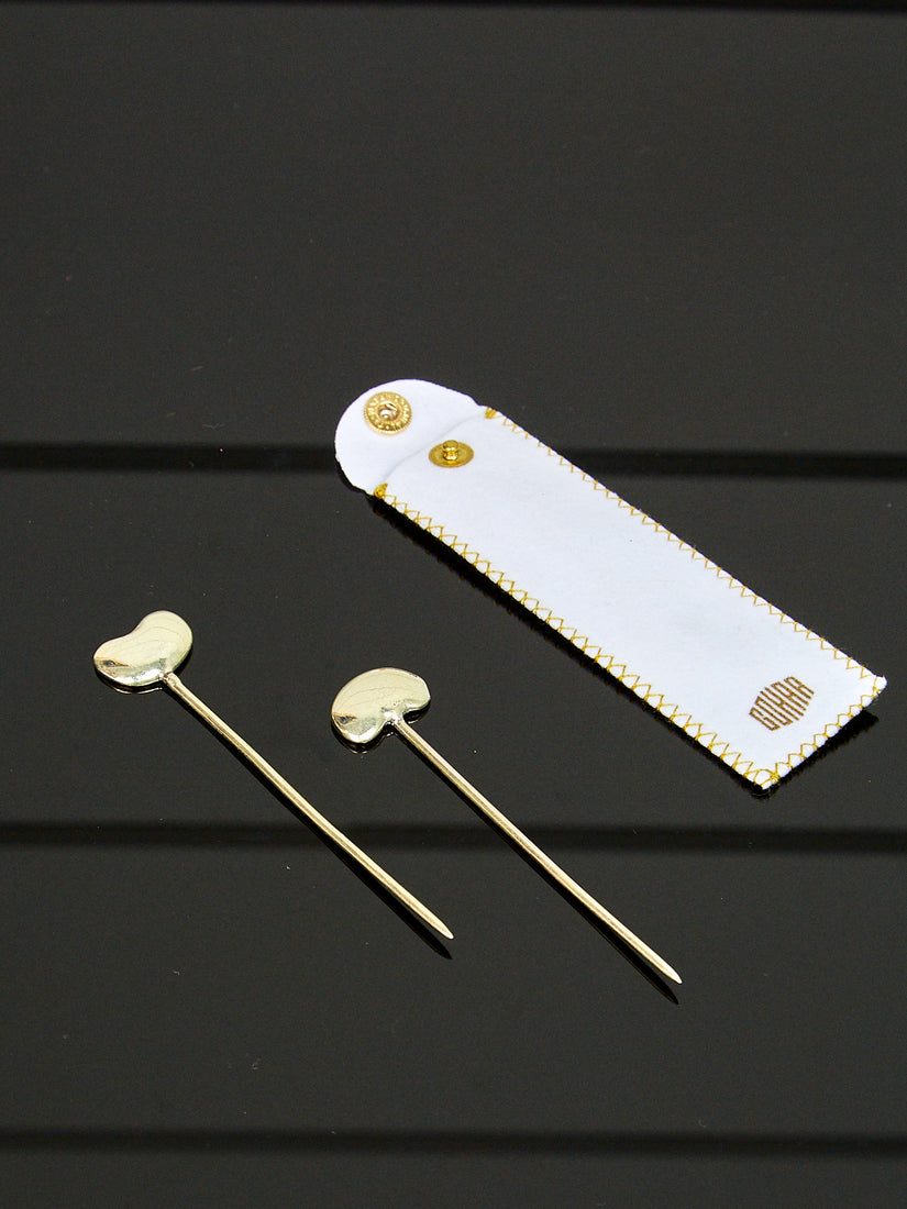 A pair of sterling silver bean toothpicks and their white pouch branded Gohar.