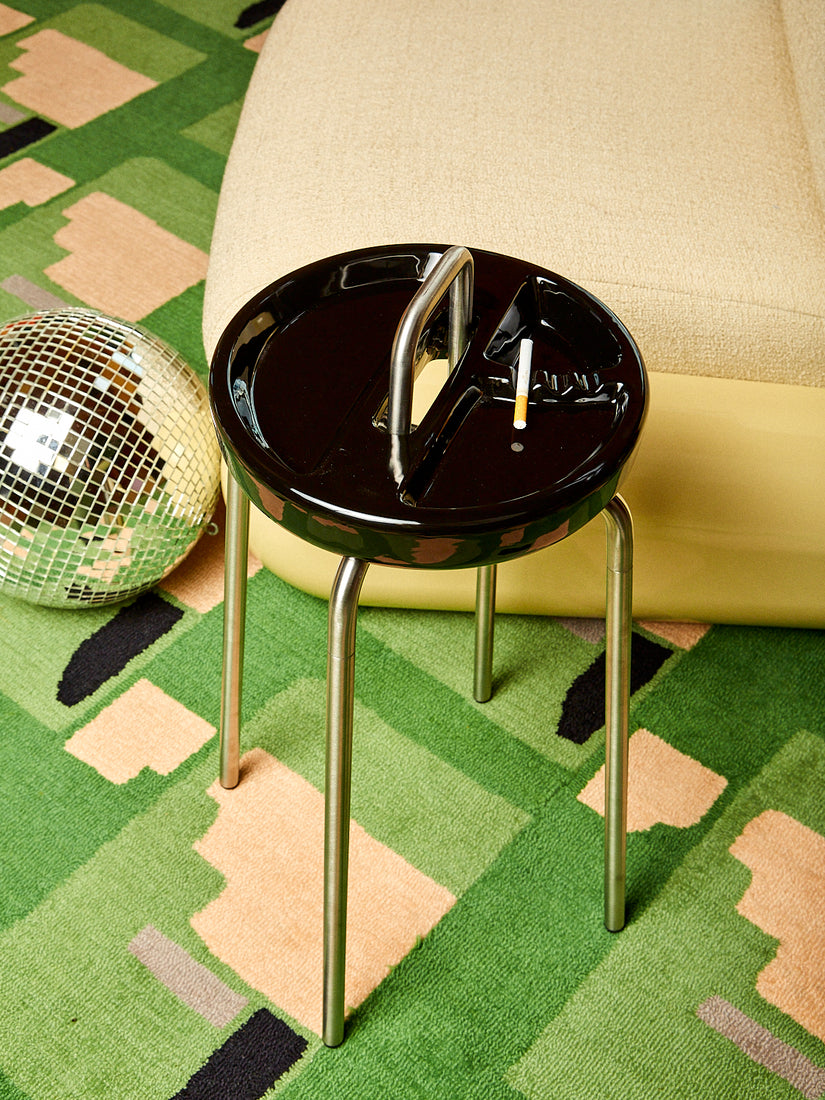 A black Side Table Ashtray with a cigarette resting inside.