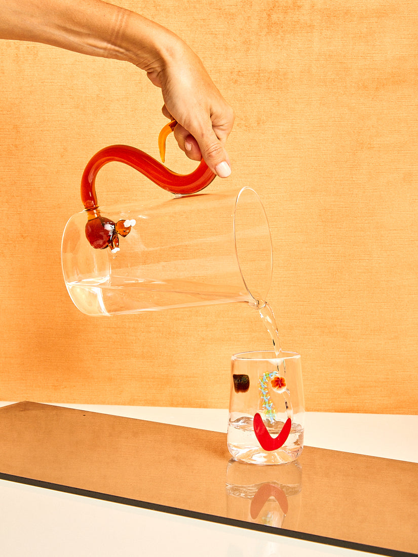 A hand pours water from the Squirrel Jug by Ichendorf Milano into a Face Vessel.