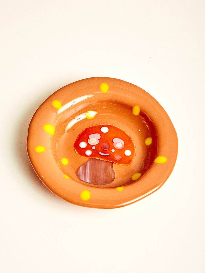 A caramel brown glass bowl with yellow dots and a red and brown mushroom with a smiley face.