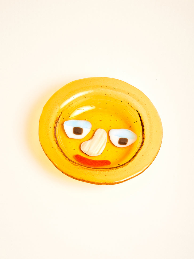 An amber glass bowl with abstract face design by Lawn Bowls.