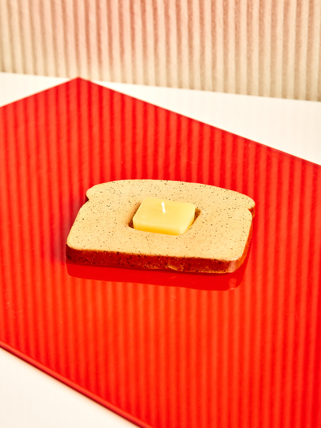 A ceramic piece of toast with an inset portion fit for a butter pat shaped tealight candle.