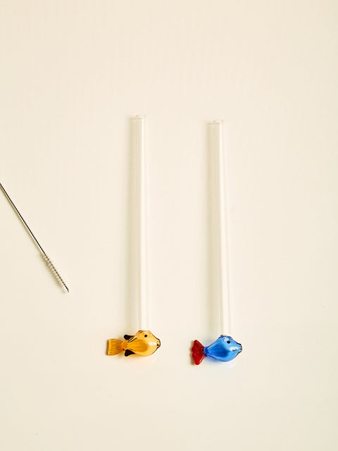 A pair of straws, one with an amber fish at the bottom, one with a blue fish at the bottom.