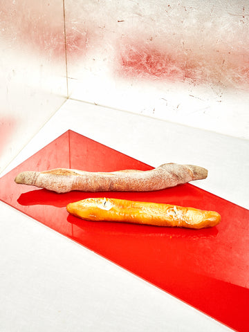 A lit baguette candle sits next to a real baguette.