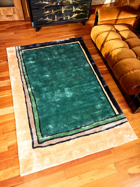 Frames Rug by Cold Picnic displayed on a wooden floor. Rug has colors of teal, black, green and cream. Fabric is a bamboo silk.