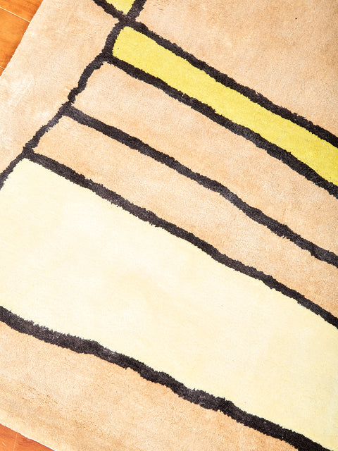 Close up picture of the details in the Time Frame Rug showing cream, tan and yellow colors.