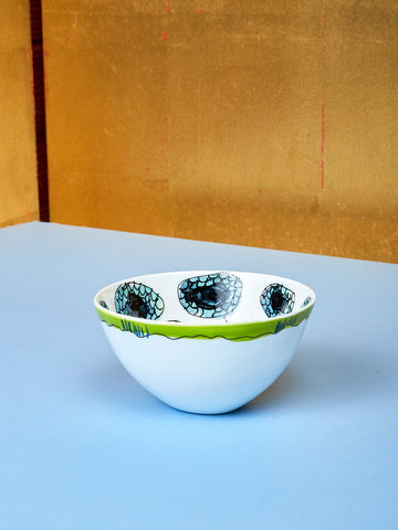 A small bowl by Marni lay on top of a blue table. 