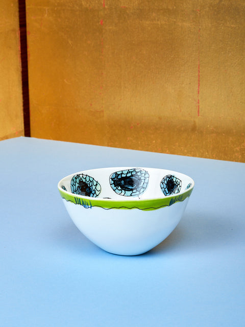 A small bowl by Marni lay on top of a blue table. 