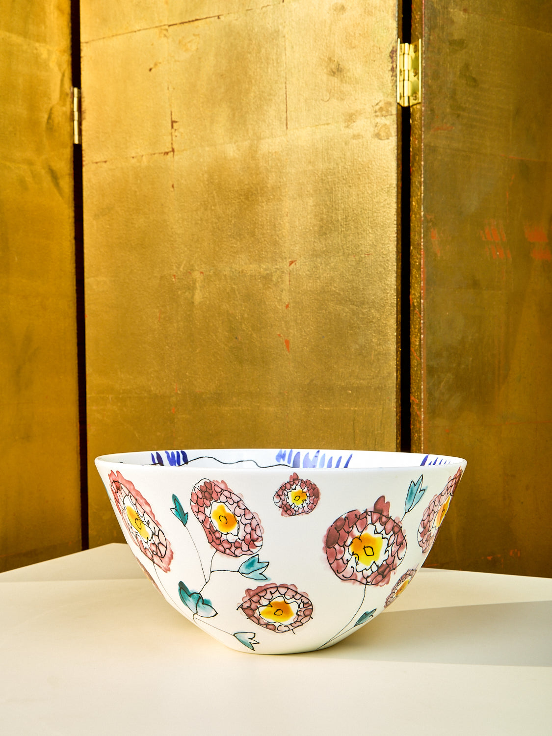 Large serving bowl by Marni sits on a cream table. Side view showing the stencils of flowers. 