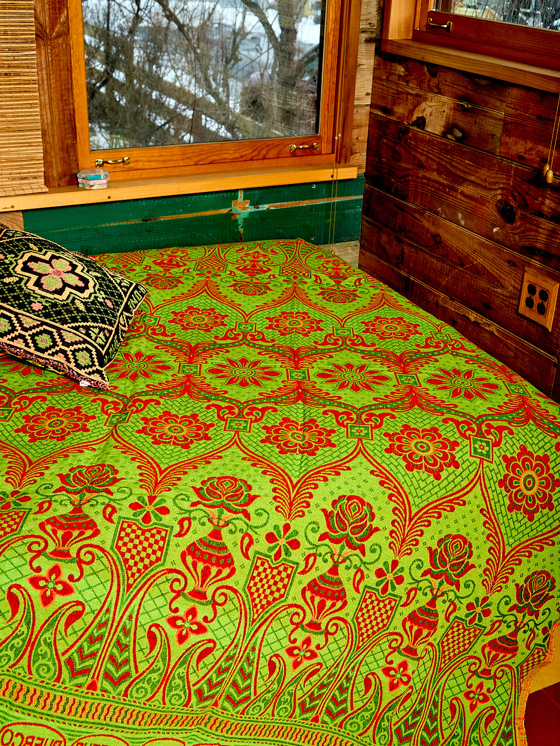 Zoom in picture of the Reversible Blanket/Rug on a bed. The picture shows the green color of the blanket/rug. 