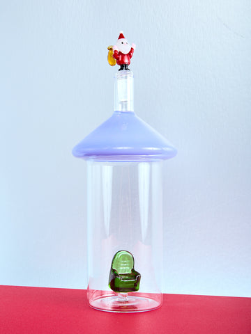 Clear bottle with a blue cap and decorative figure on a red surface with a light blue background