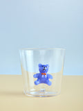 Clear glass with a blue teddy bear figurine on a light blue background
