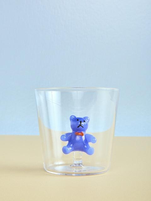 Clear glass with a blue teddy bear figurine on a light blue background
