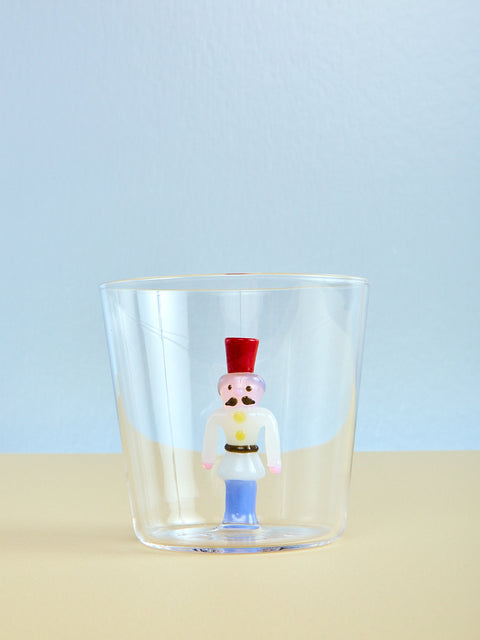 Clear glass with a decorative nutcracker figure inside on a light blue background