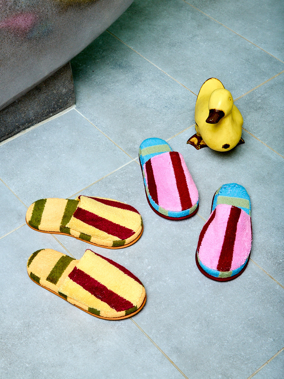 Colorful slippers and a rubber duck on a tiled floor
