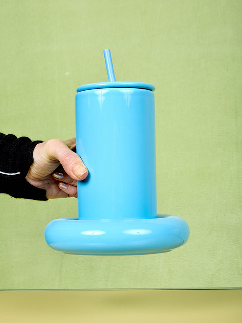 Blue Gustaf Westman tumbler with a straw