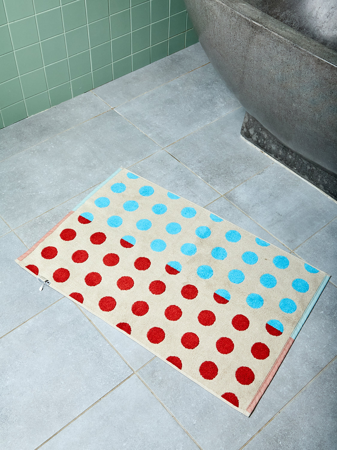 Polka dot bath mat on a tiled bathroom floor