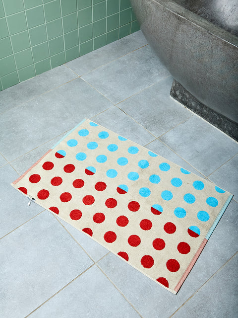 Polka dot bath mat on a tiled bathroom floor