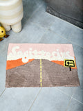 Bathmat with an open road design and text reading "Sagittarius" on a tile floor