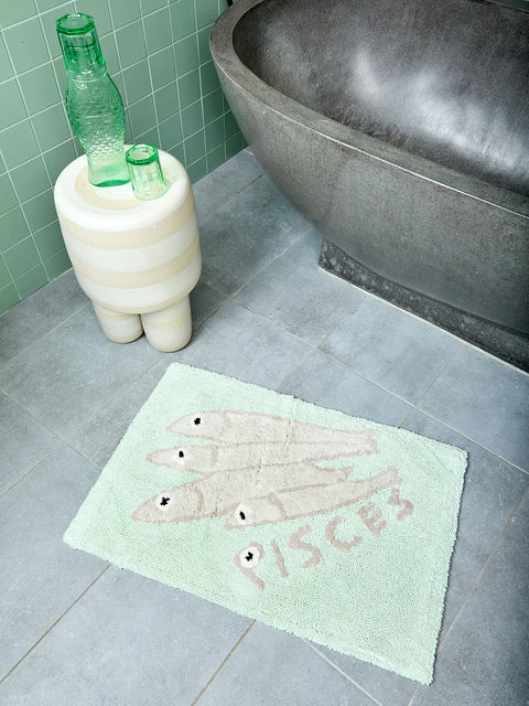 Mint bathmat with four grey fish and text that reads "PISCES" on a bathroom floor.
