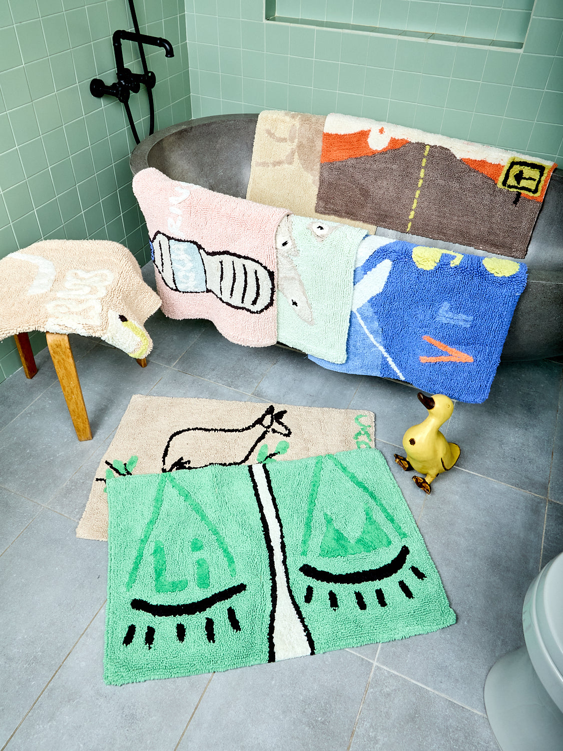 Assorted zodiac-themed bathmats on a bathroom floor and splayed over a bathtub