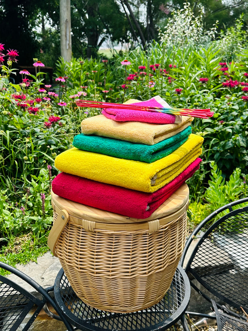 A stack of Dusen Dusen's reversible bath and hand towels sitting on top of a picnic cooler basket.